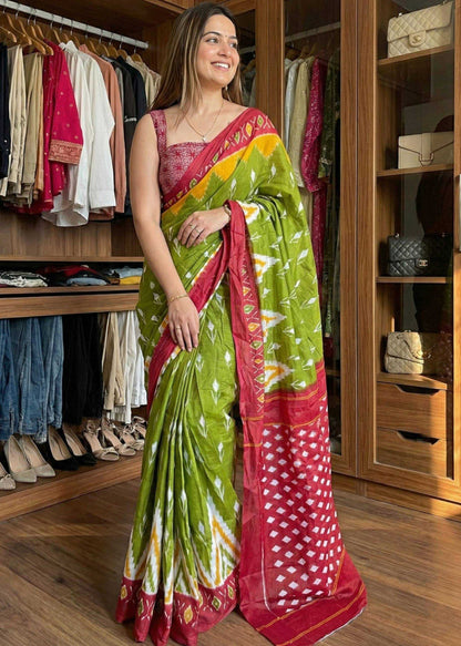 Woman wearing a green and red saree in a clothing store.