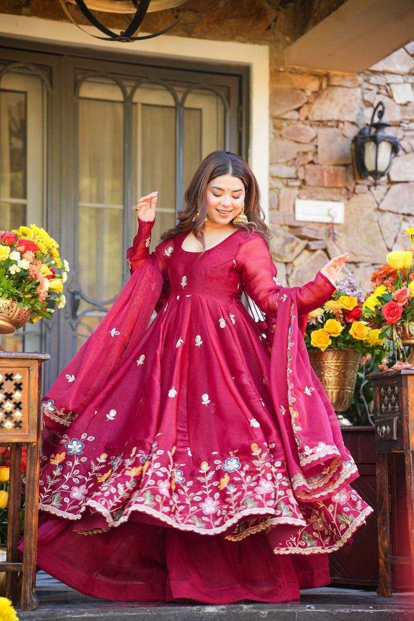 Woman in a red traditional outfit standing outdoors with floral decorations.