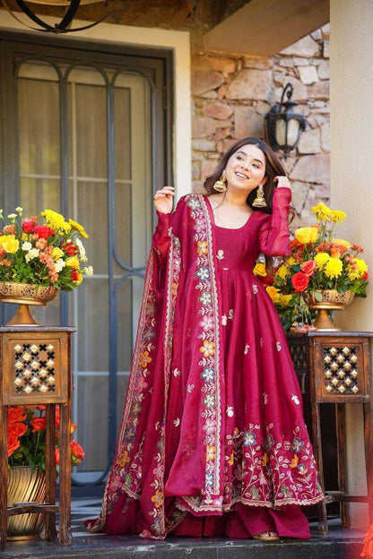 Woman in a red embroidered traditional outfit standing between two tables with floral arrangements.